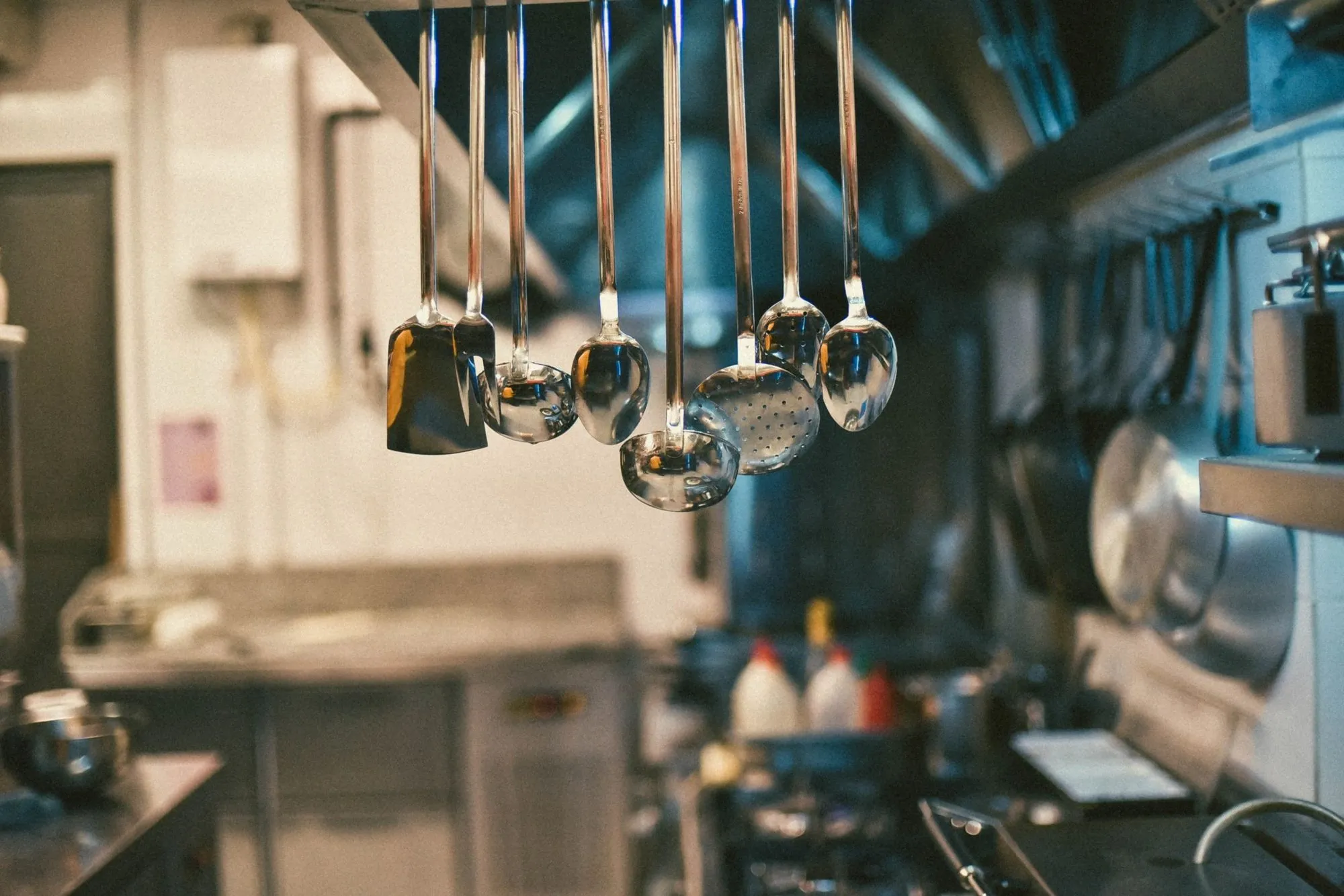 Stainless steel ladles hanging above a commercial kitchen line