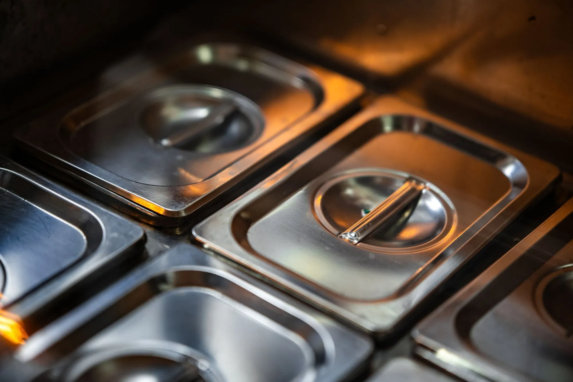 Close view of stainless steel food containers with lids in a commercial kitchen